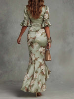 Celestina | Elegante Vestido Largo de Satén Verde con Estampado Floral, Mangas Acampanadas con Volantes, Escote en V y Bajo Asimétrico